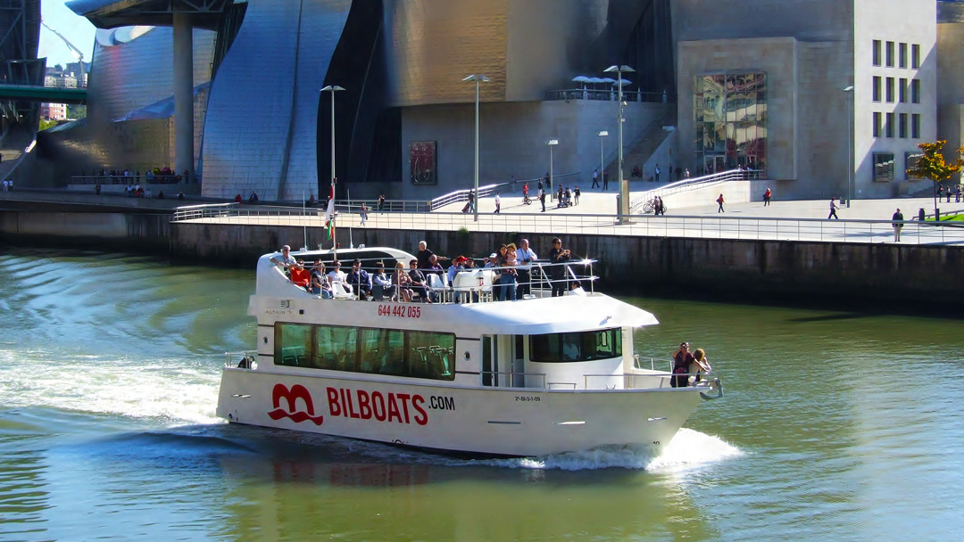 Turistas a bordo del barco Bilboats con el Museo Guggenheim de fondo